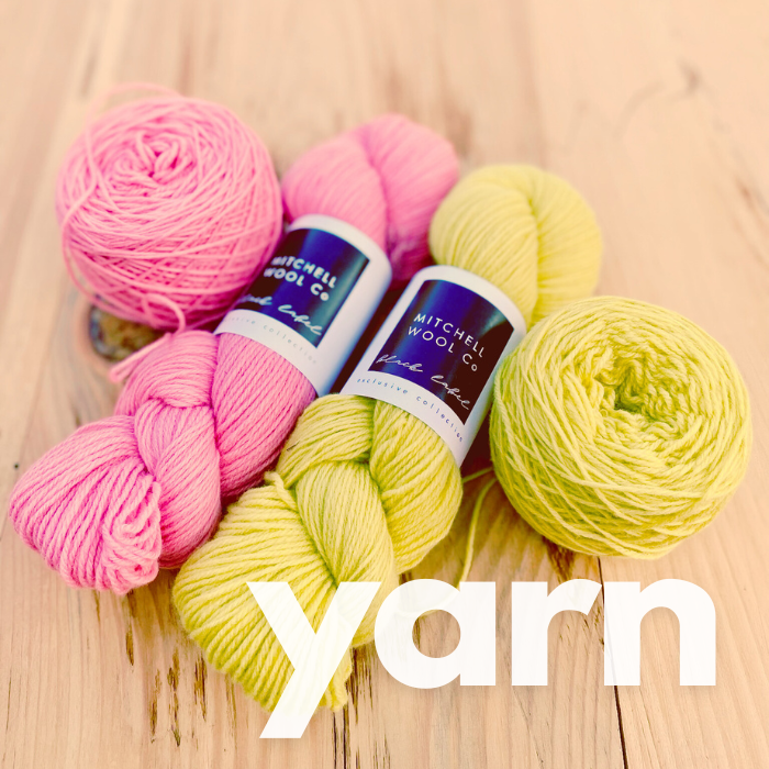 A closeup of a farm yarn knitted sweater with modern stitch patterns. It is worn by a light skinned human and 