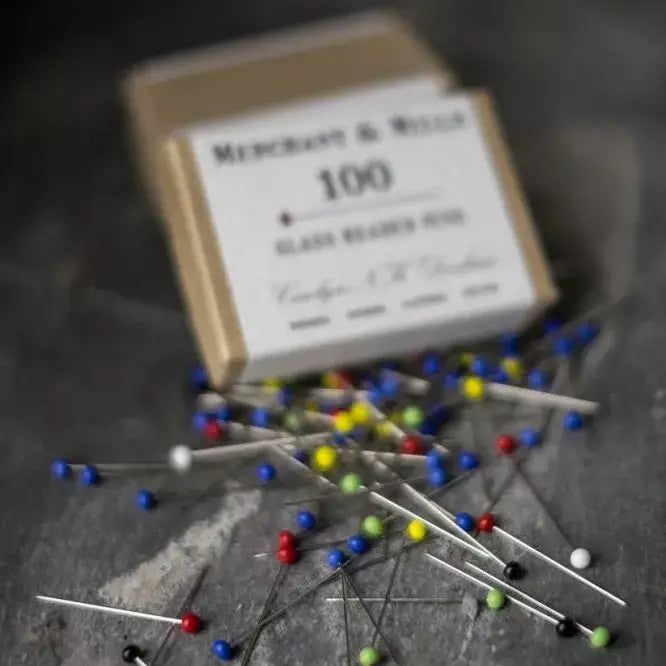 Box of pins with colorful heads on a dark surface