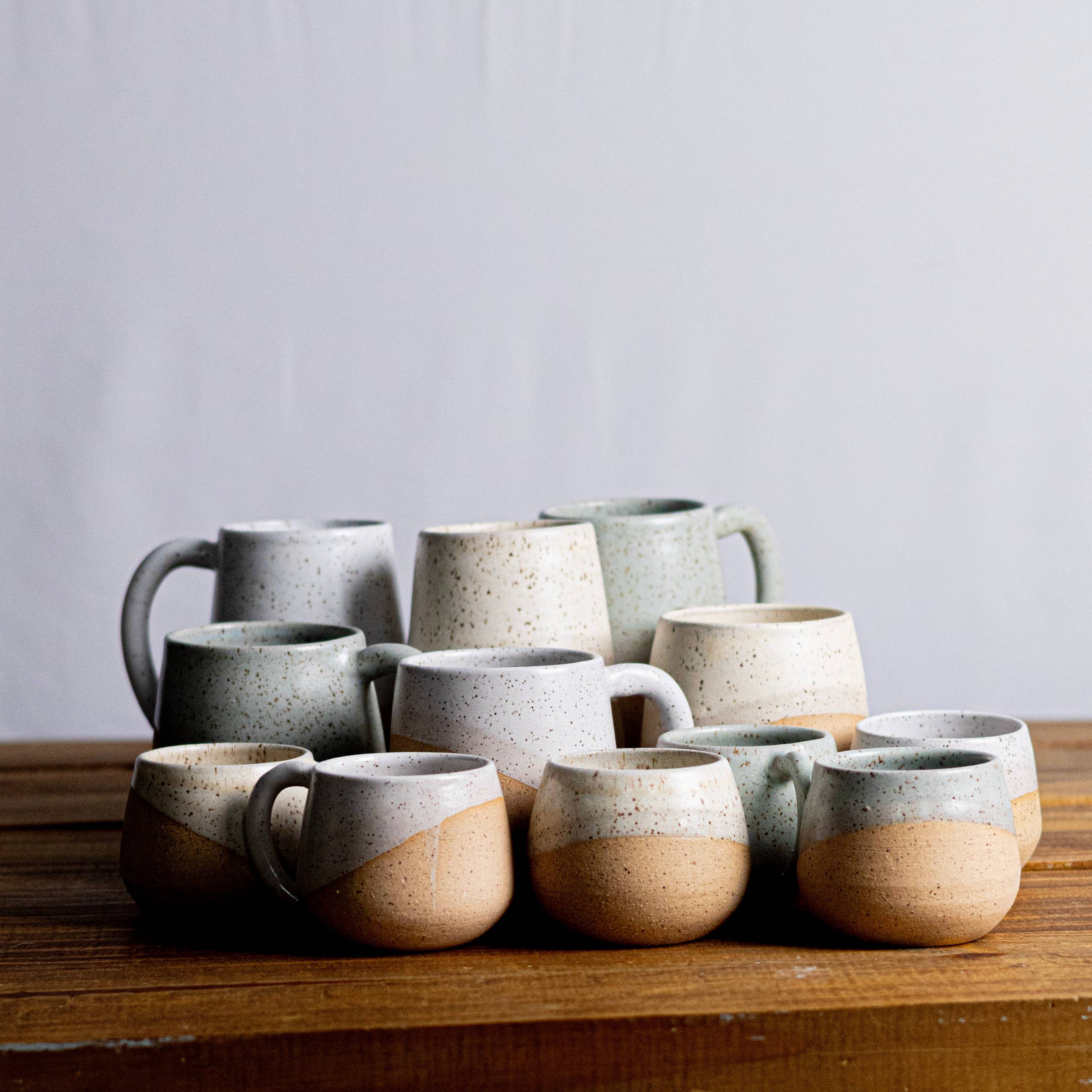 Set of ceramic mugs on a wooden surface with a plain background