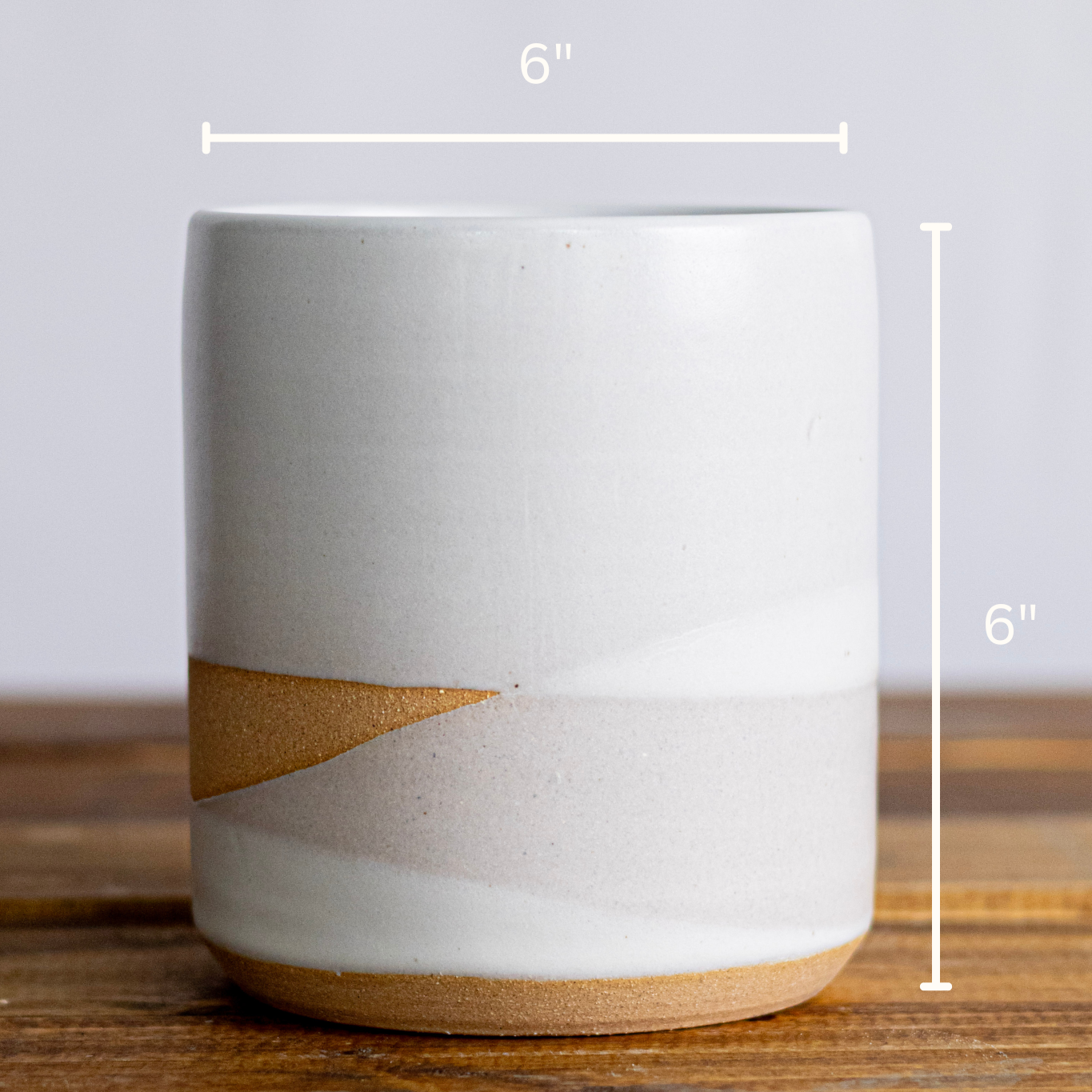 Ceramic mug with brown accent on a wooden surface, dimensions indicated.