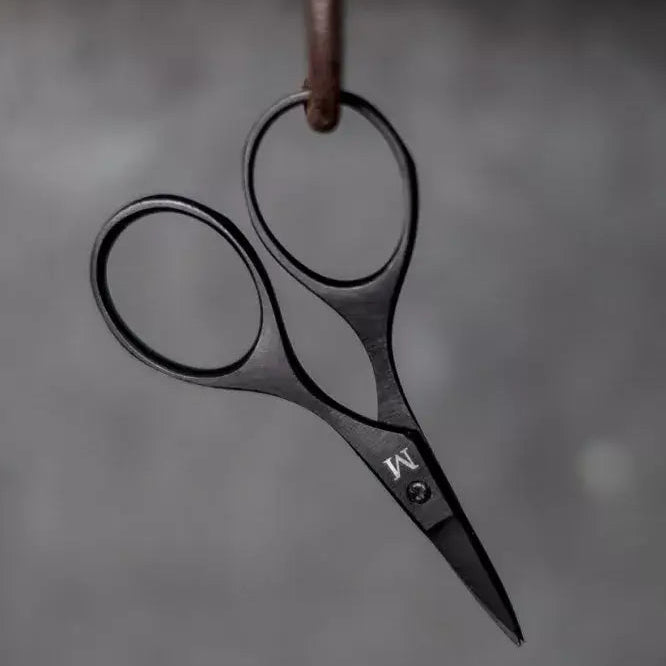 Pair of black-handled scissors hanging on a hook against a gray background