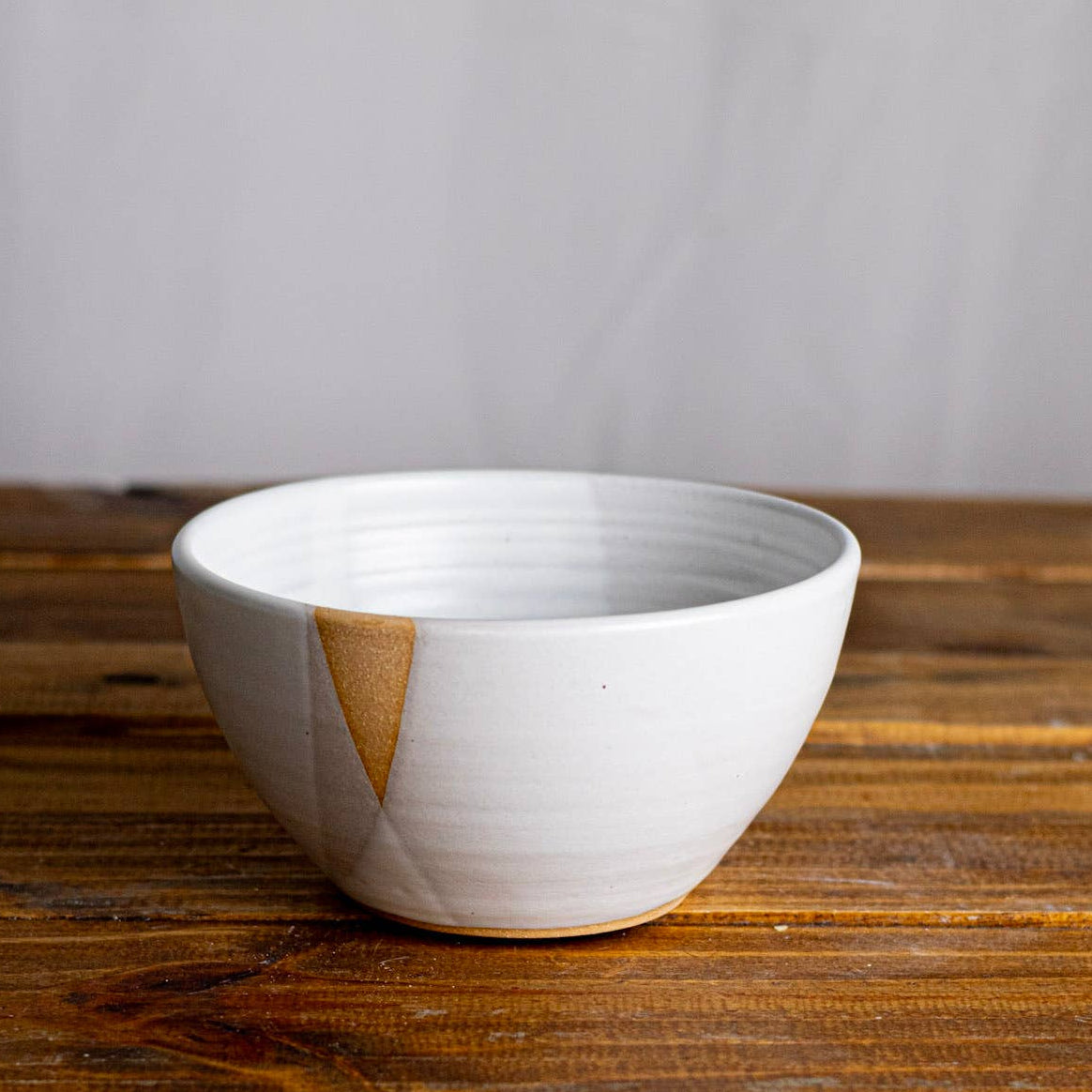 White ceramic bowl on a wooden surface with a plain background