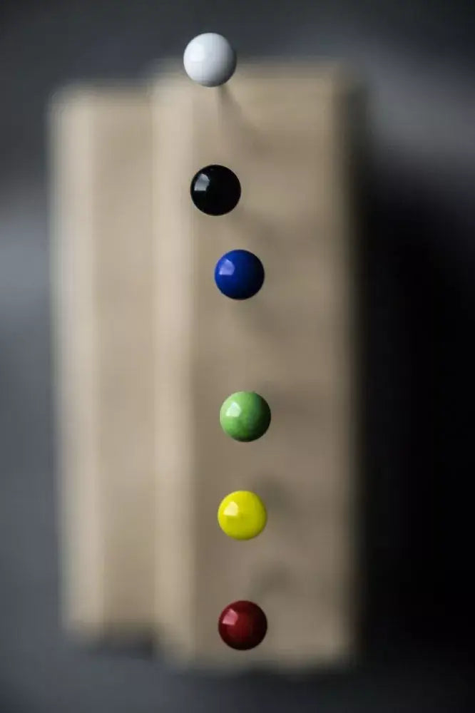 Colorful pins on a wooden block against a dark background
