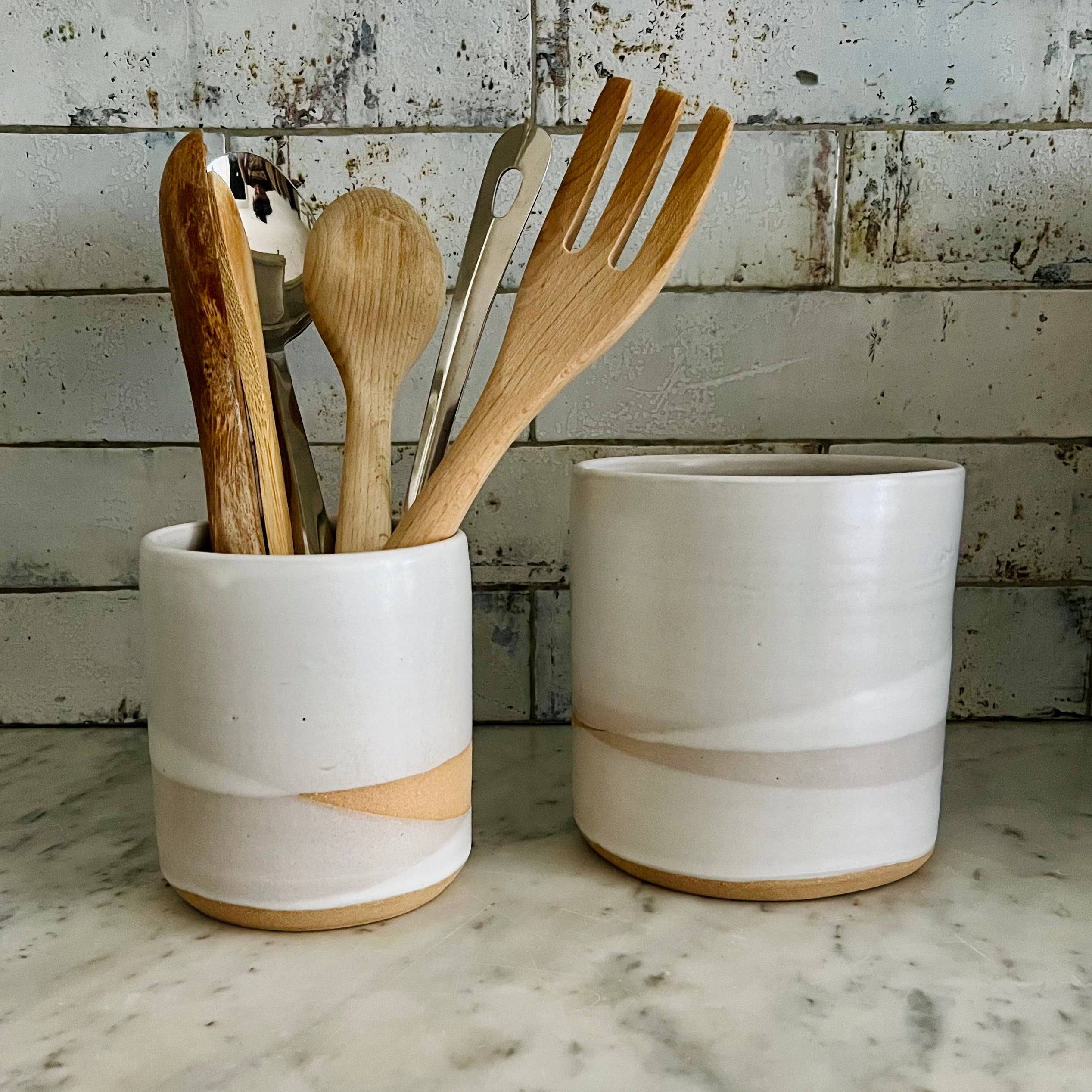 Two ceramic containers with wooden utensils on a marble countertop. WE SELL THE LARGE SIZE ONLY