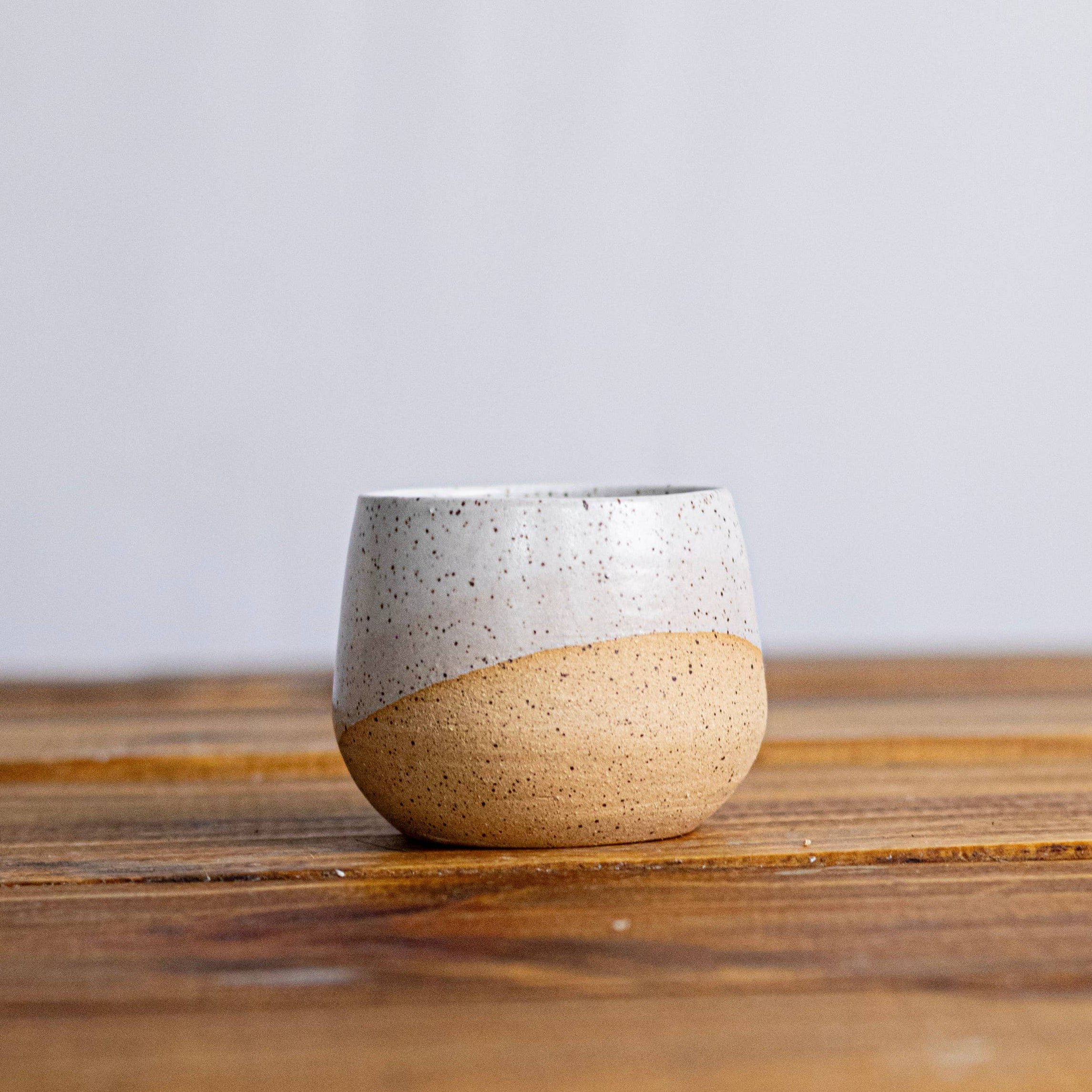 Ceramic cup with two-tone design on a wooden surface