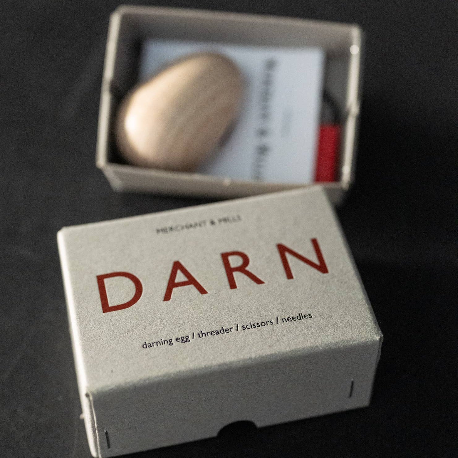 Small box labeled 'DARN' containing a wooden object on a dark background