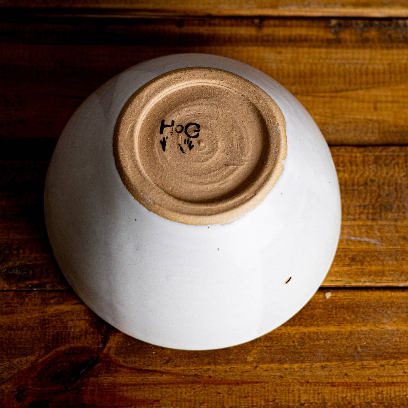 White ceramic bowl with a brown bottom on a wooden surface