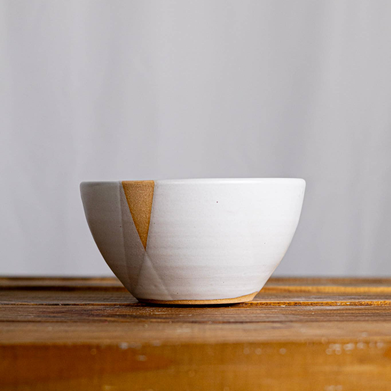 White ceramic bowl with wooden base on a wooden surface