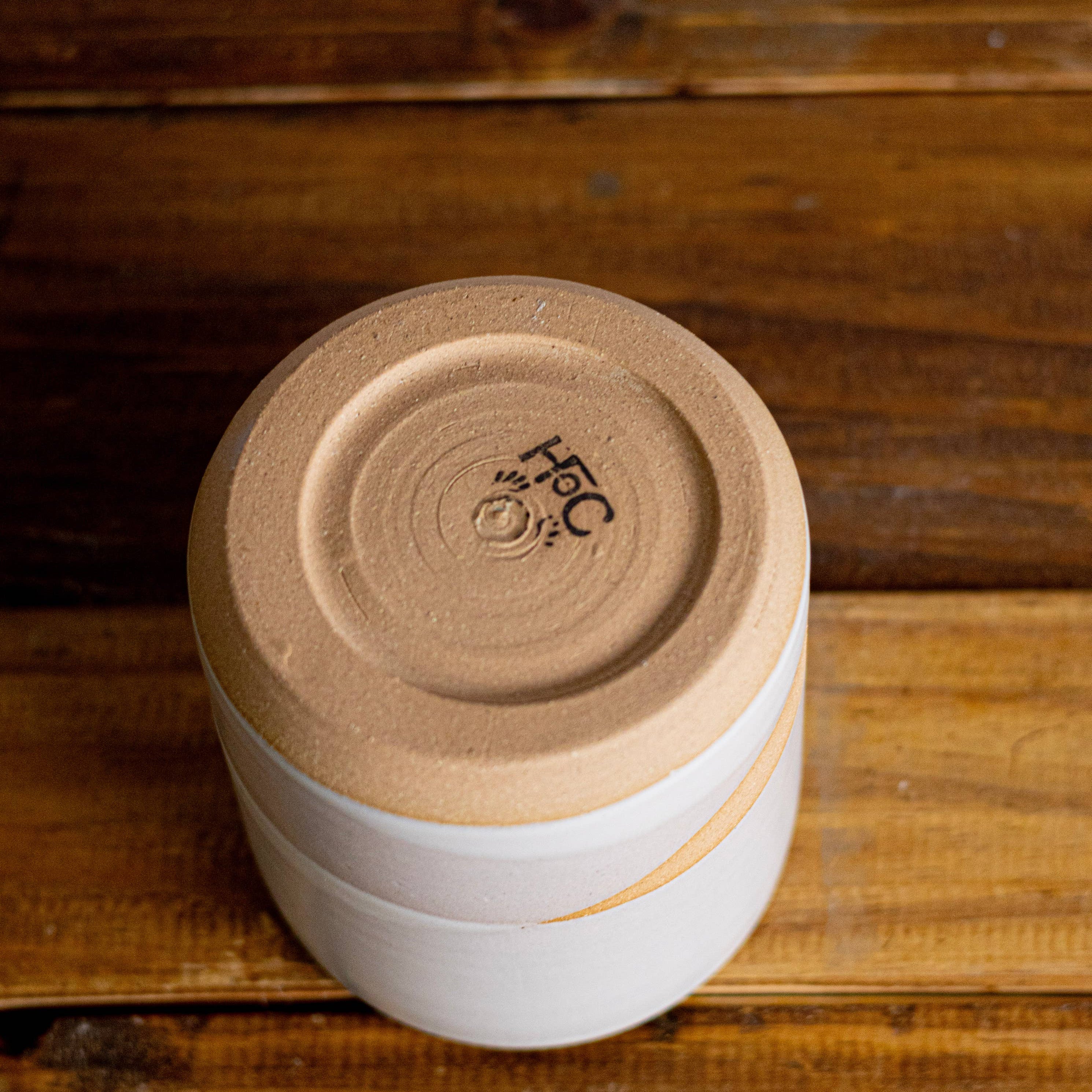 Stack of white containers with a brown lid on a wooden surface