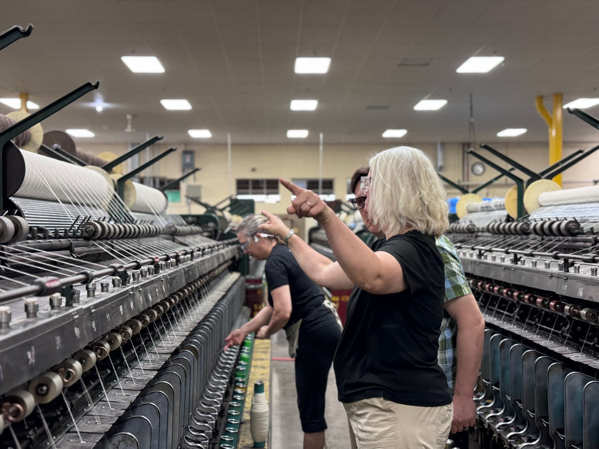Cindy gives direction to the mill manager while an expert changes inspects the yarn