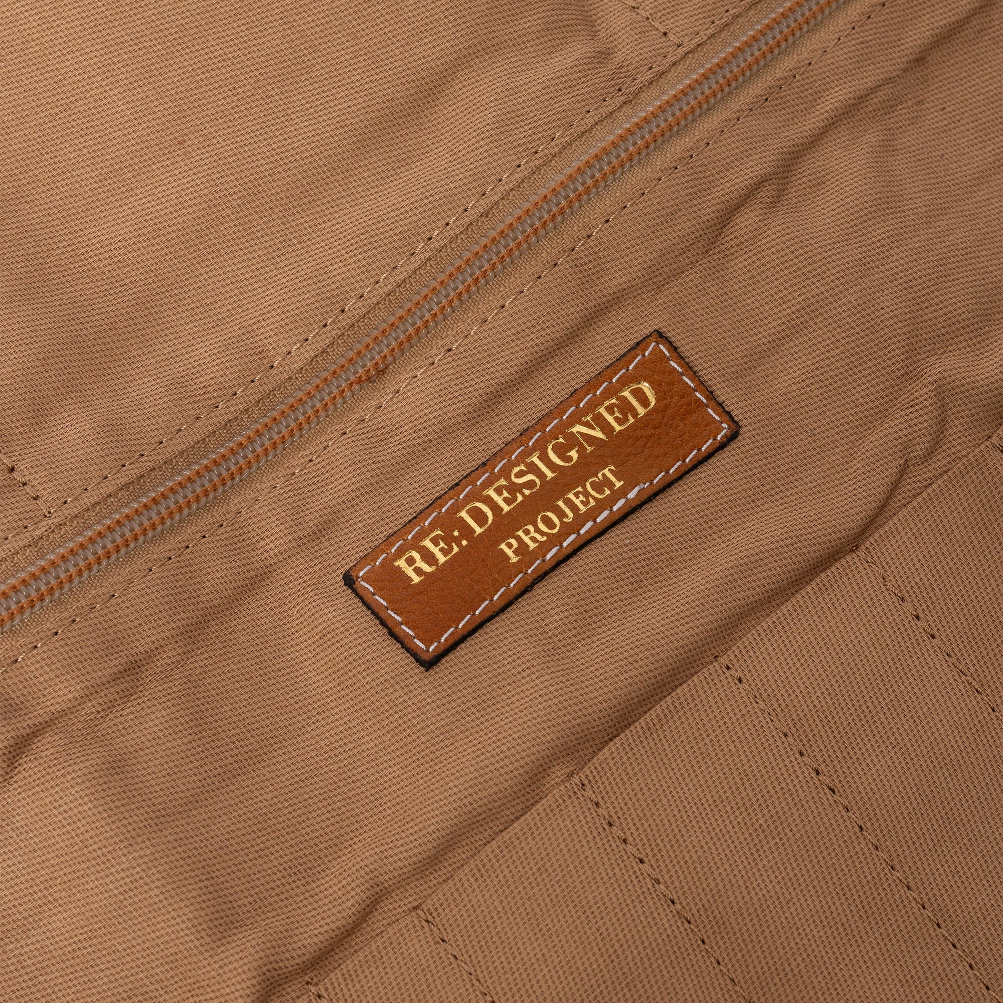 Close-up of a brown fabric surface with a 'RE-DESIGNED PROJECT' label.