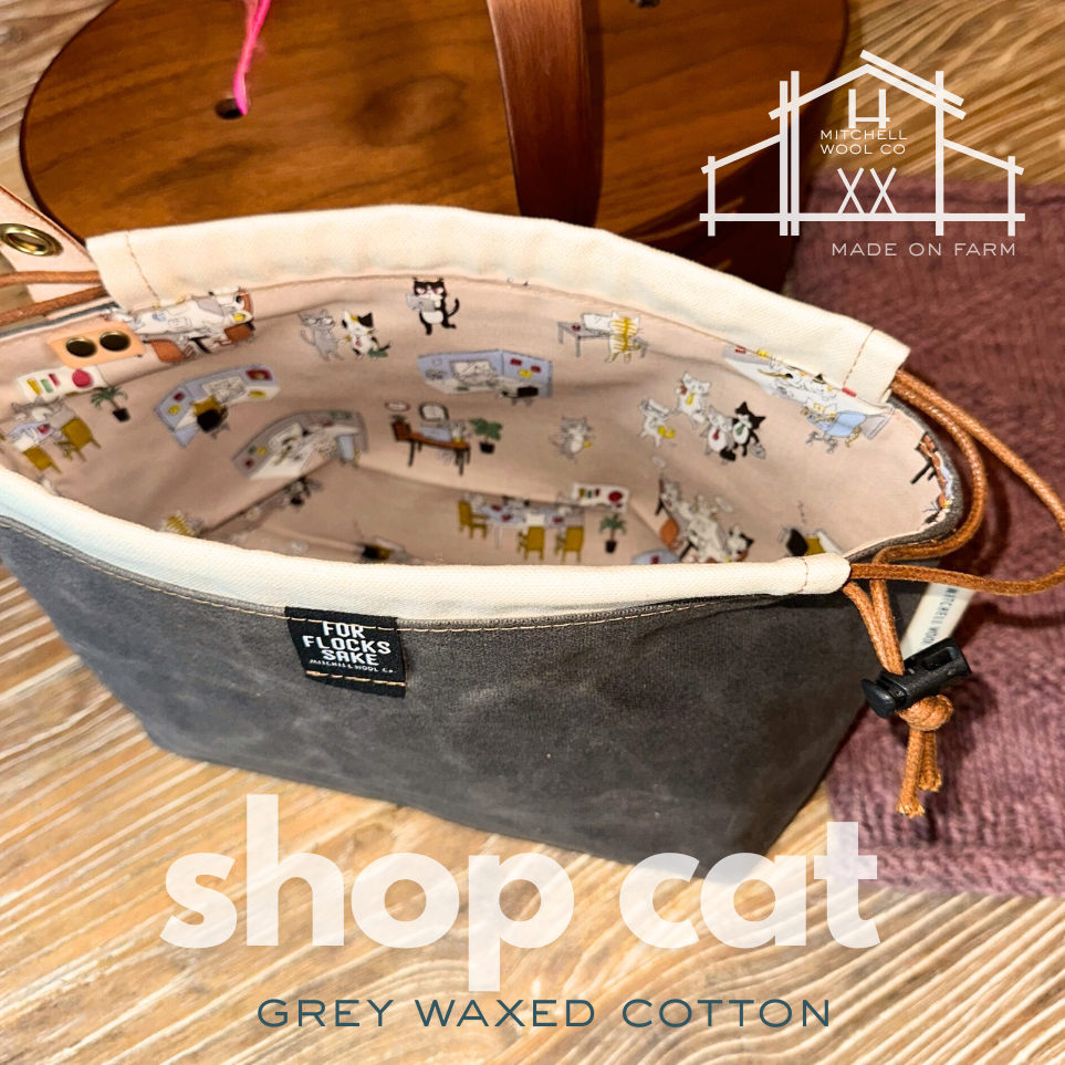 Gray waxed cotton bag with illustrations of a store interior on a wooden surface, featuring 'Mitchell & Main Co' branding.