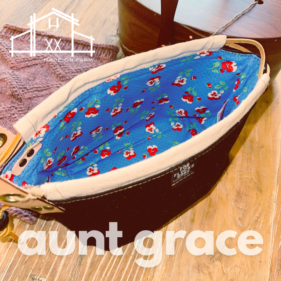 Vintage Floral-patterned & black waxed project bag with 'aunt grace' text on a wooden surface, featuring 'made on farm' branding.