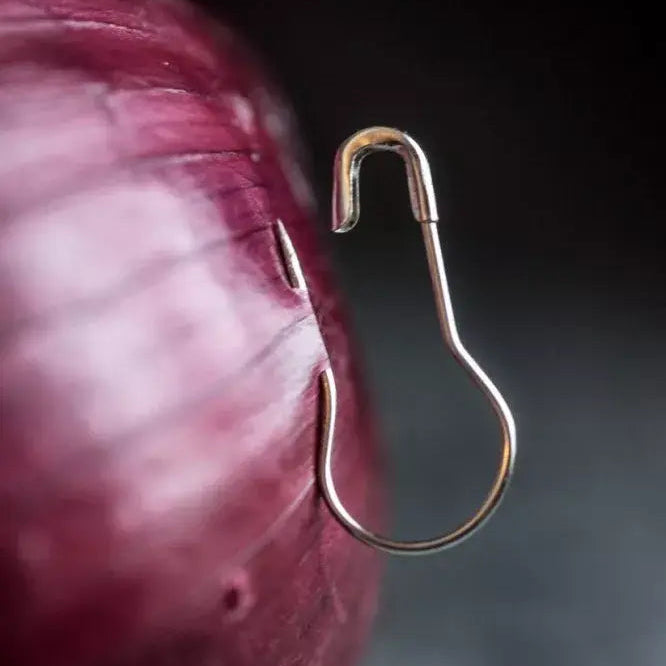 Close-up of a gold safety pin against a onion on a dark background