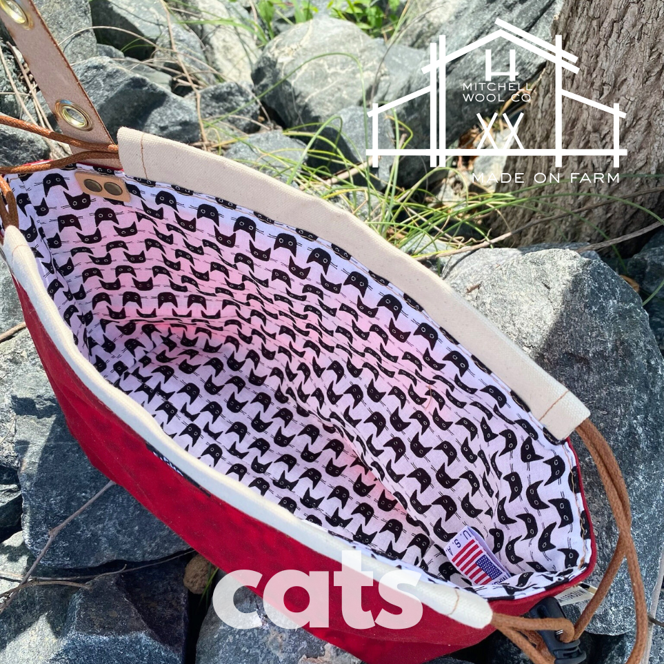 Red waxed cotton with a black cat interior on rocks, featuring 'Mitchell Wool Co.' logo.