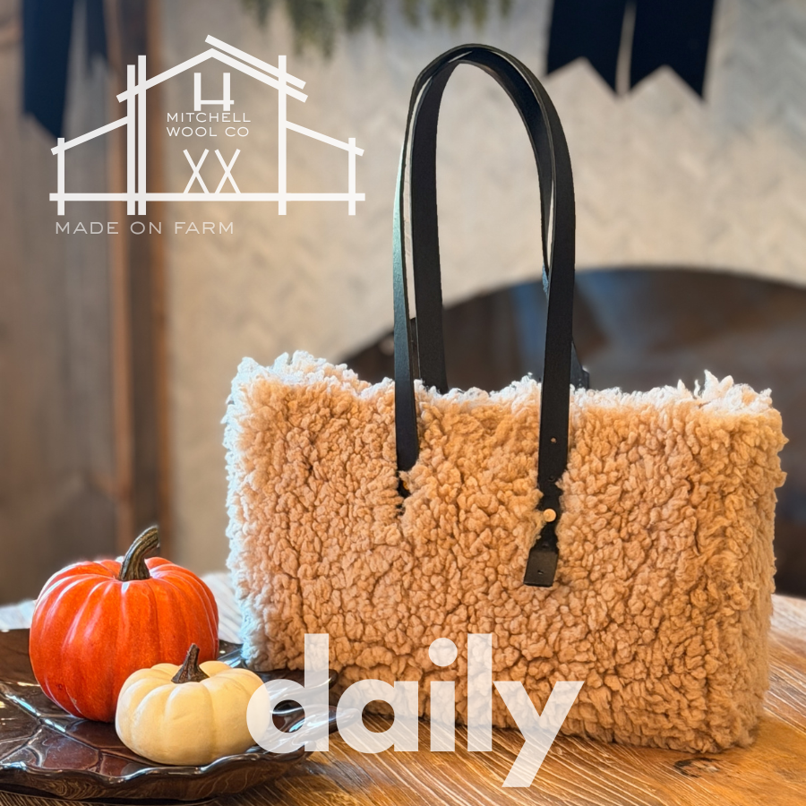 Beige textured tote bag with black handles on a wooden surface with pumpkins, featuring 'Mitchell Wool Co' and 'daily' branding.