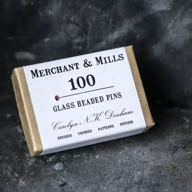 Box of Merchant & Mills glass headed pins on a dark textured background
