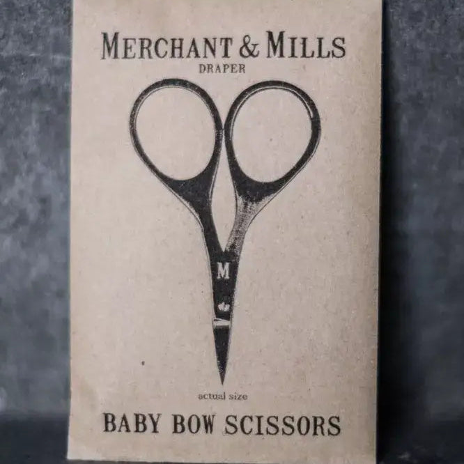 Card with illustration of scissors and text 'Merchant & Mills Draper Baby Bow Scissors' on a textured background