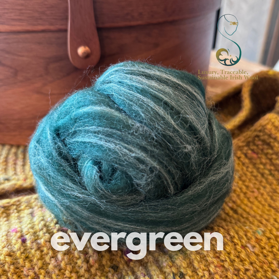 Spruce green dollup of combed top from BFL Irish sheep labeled 'evergreen' on a textured surface with a wooden box in the background. 