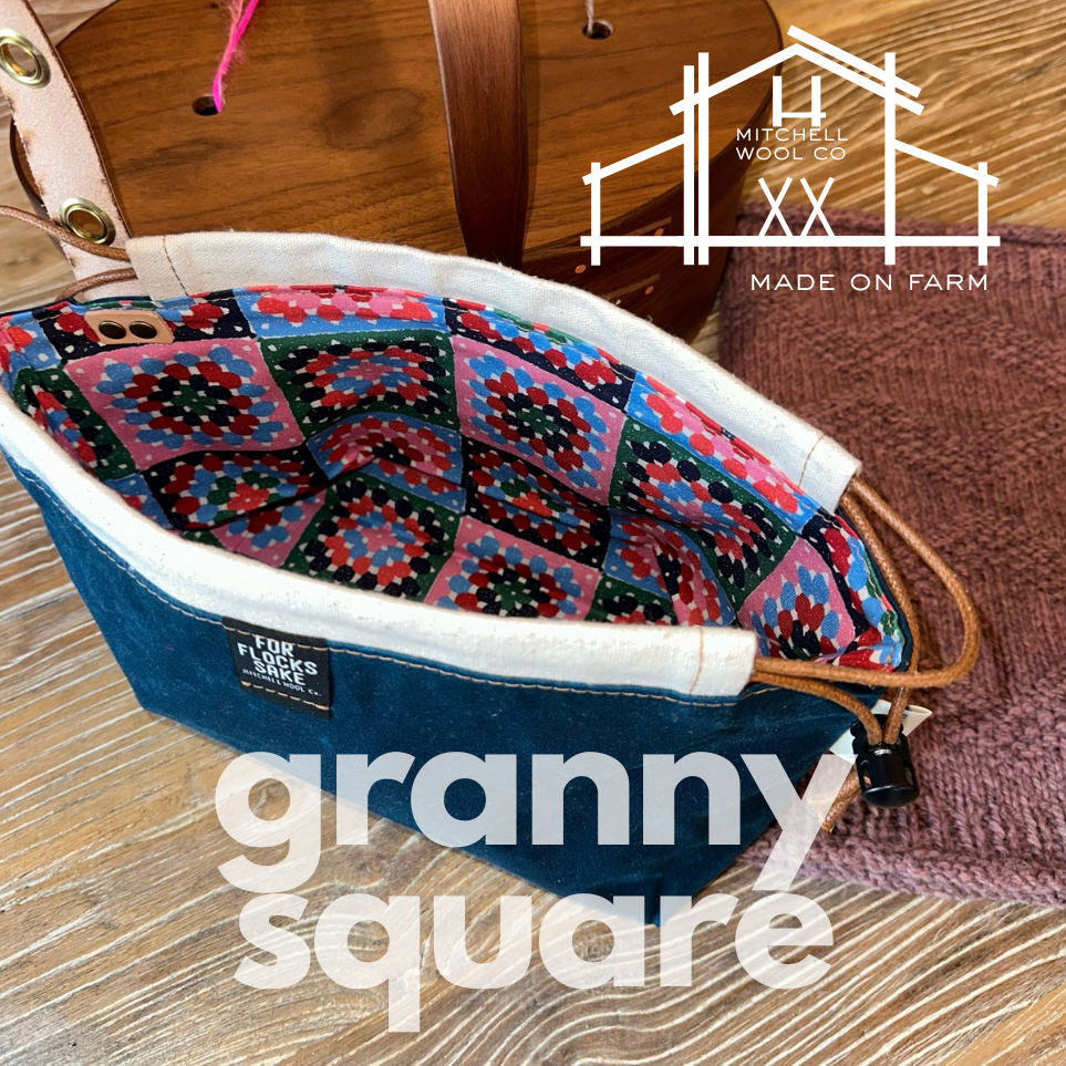 Project bag with colorful granny square pattern on a wooden surface, featuring Mitchell Wool Co branding.