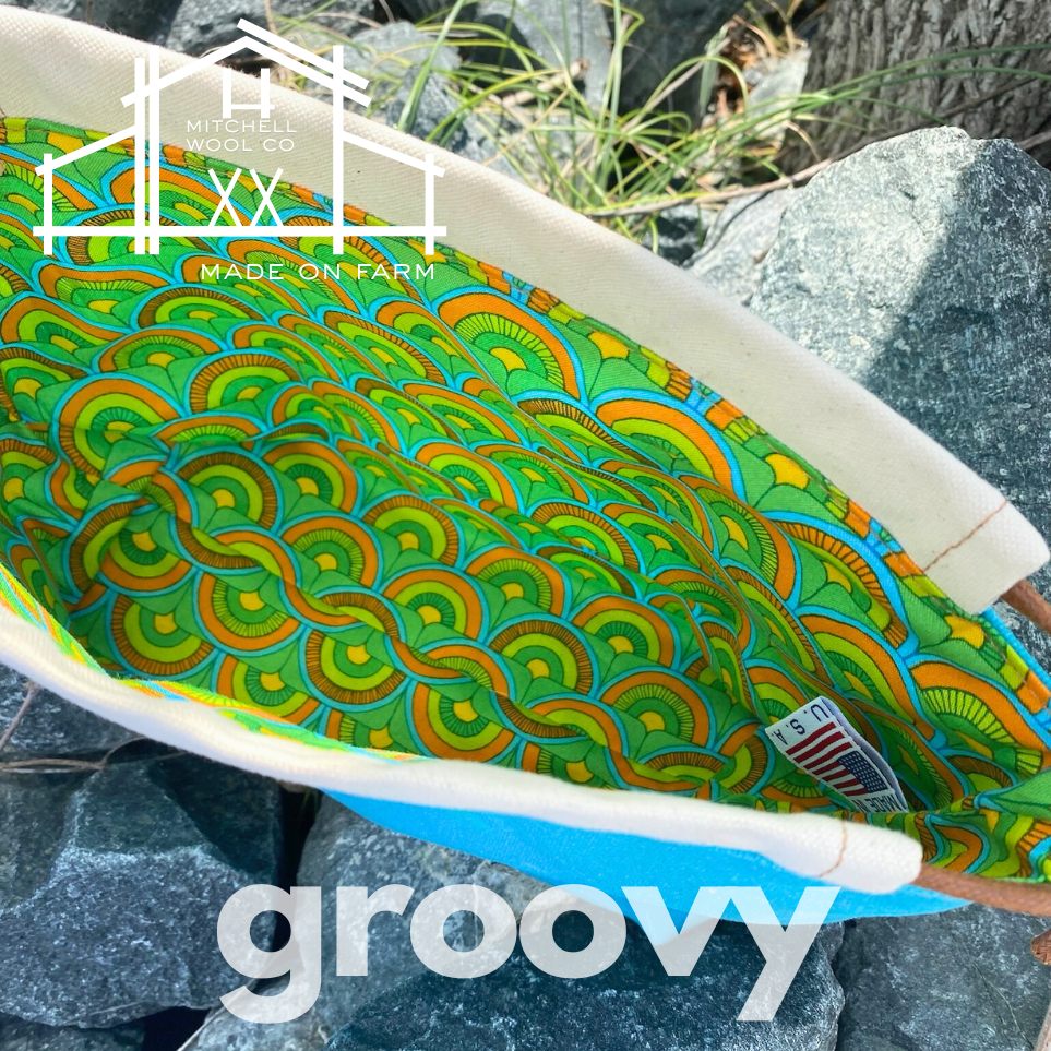 Colorful patterned project bag on a rock with 'groovy' text and 'Mitchell & Main' branding.