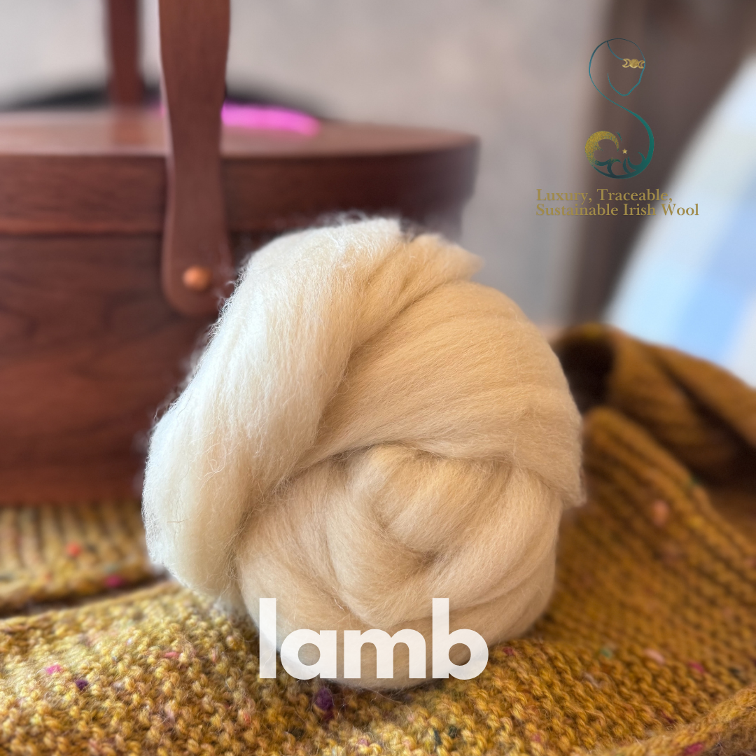 Ball of creamy beige combed top labeled 'lamb' on a textured surface with a blurred background