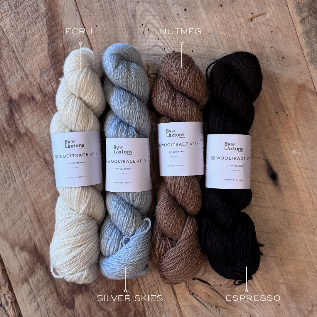 Four nuetral skeins of yarn with a Laxtons label sit on an old wood floor