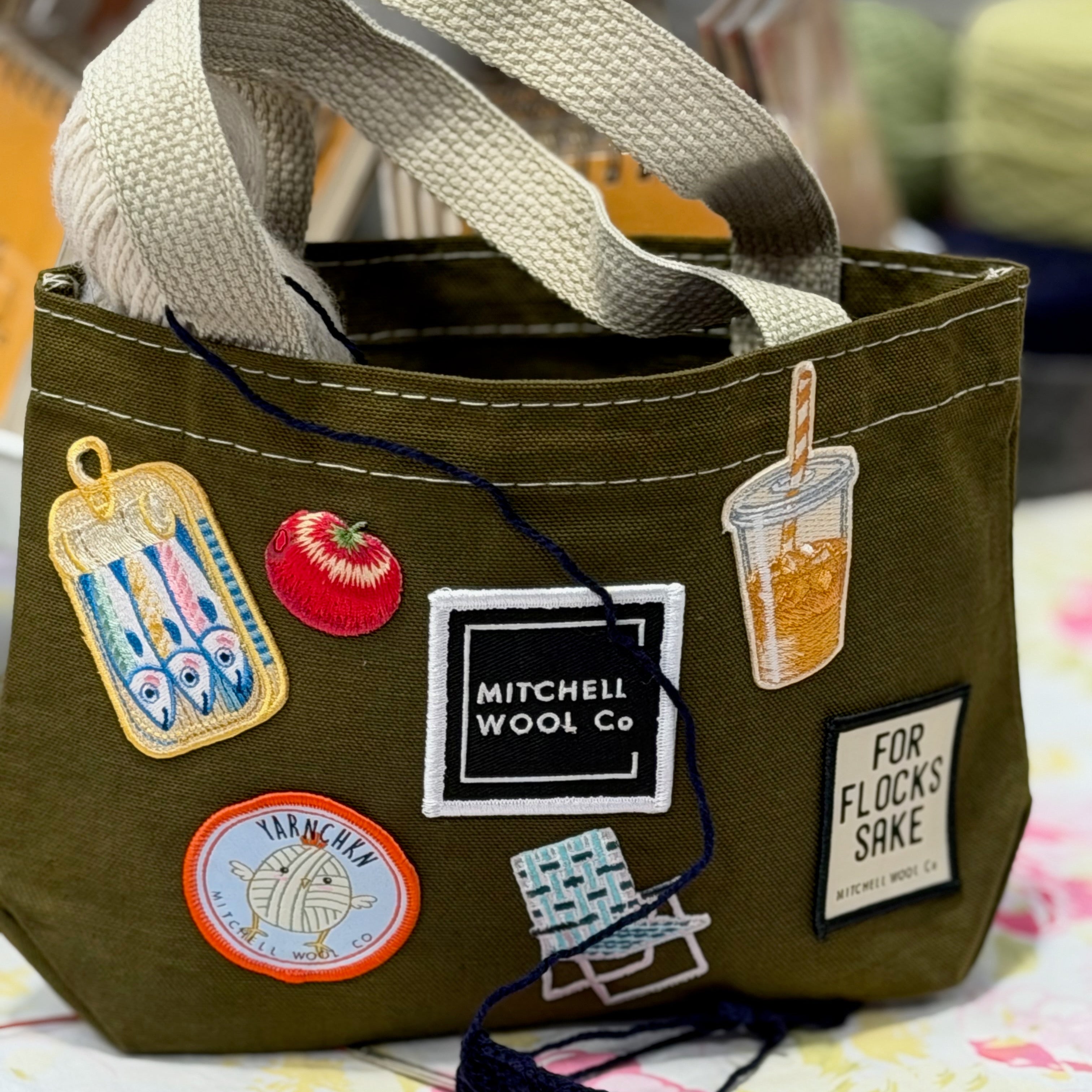 Green bag with patches and a strap on a floral surface