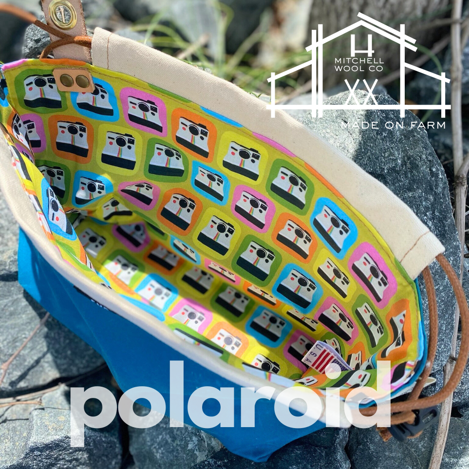 Colorful patterned bag with Polaroid logo on a stone surface, featuring Mitchell Wool Co branding.