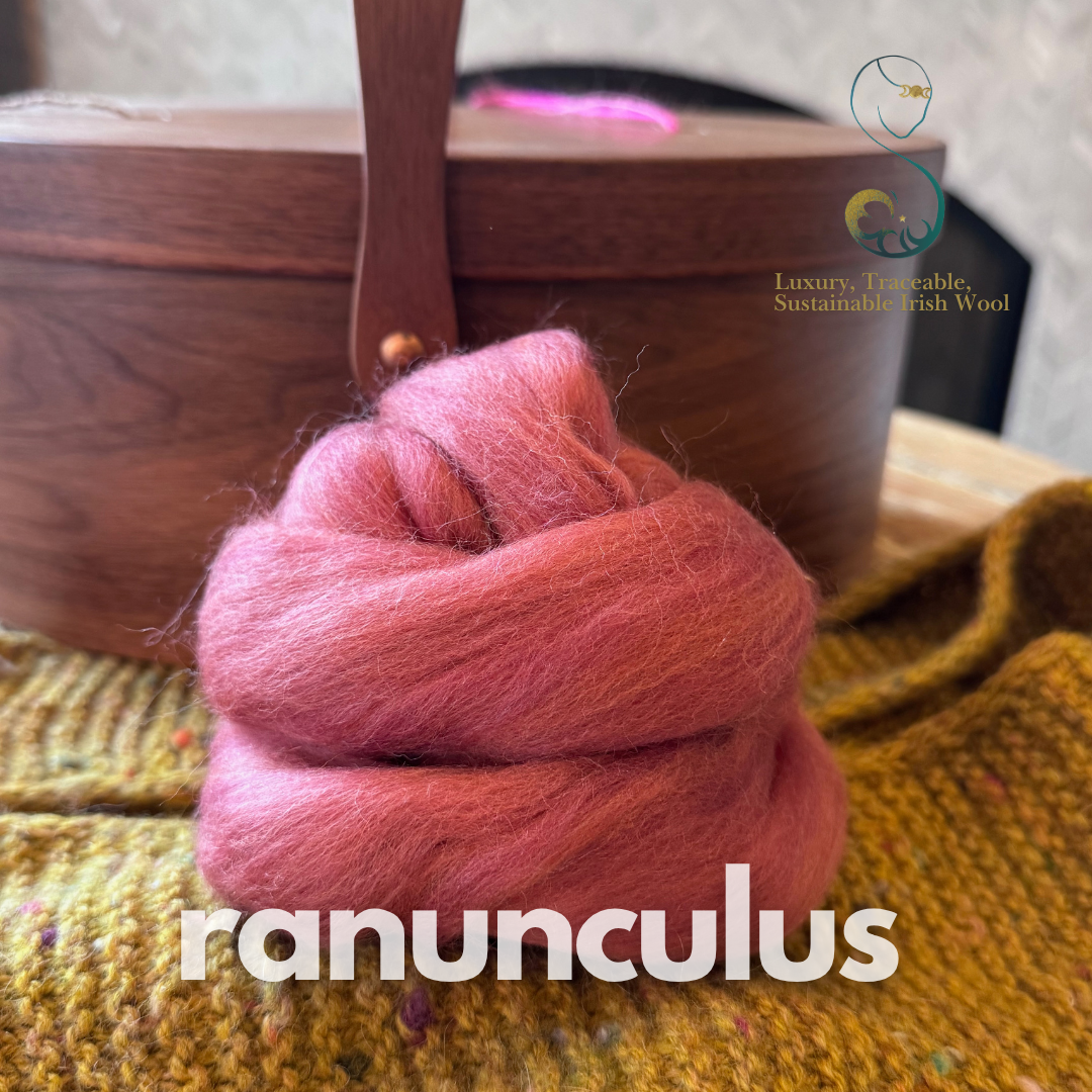 Pink dollup of combed top from BFL Irish sheep on a textured surface with a wooden box in the background, featuring the brand 'ranunculus'.