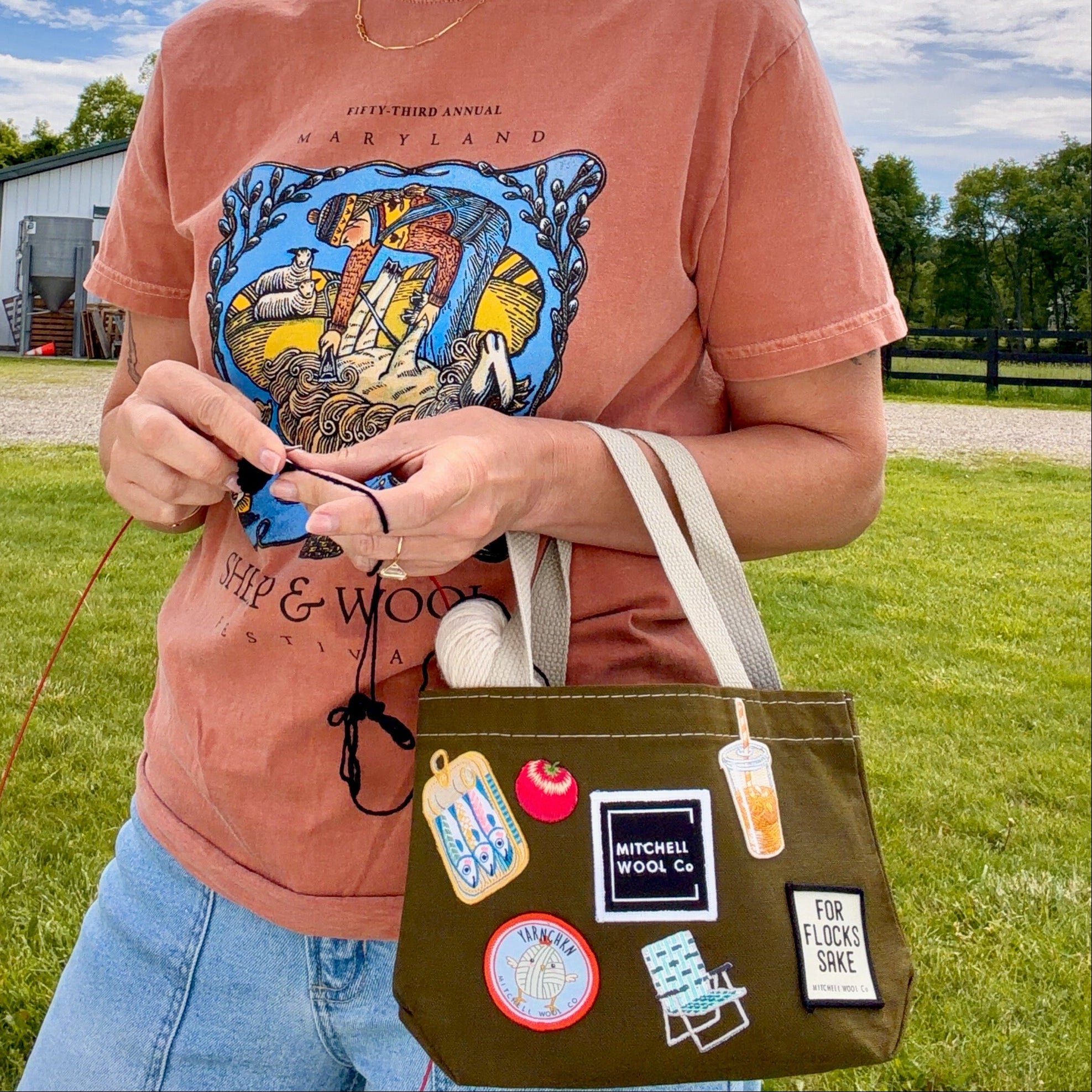 Person holding a bag with patches outdoors on a cloudy day