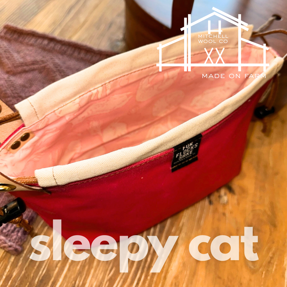 bright pink waxed cotton project bag with pink interior on a wooden surface, featuring 'Mitchell Wool Co' branding.