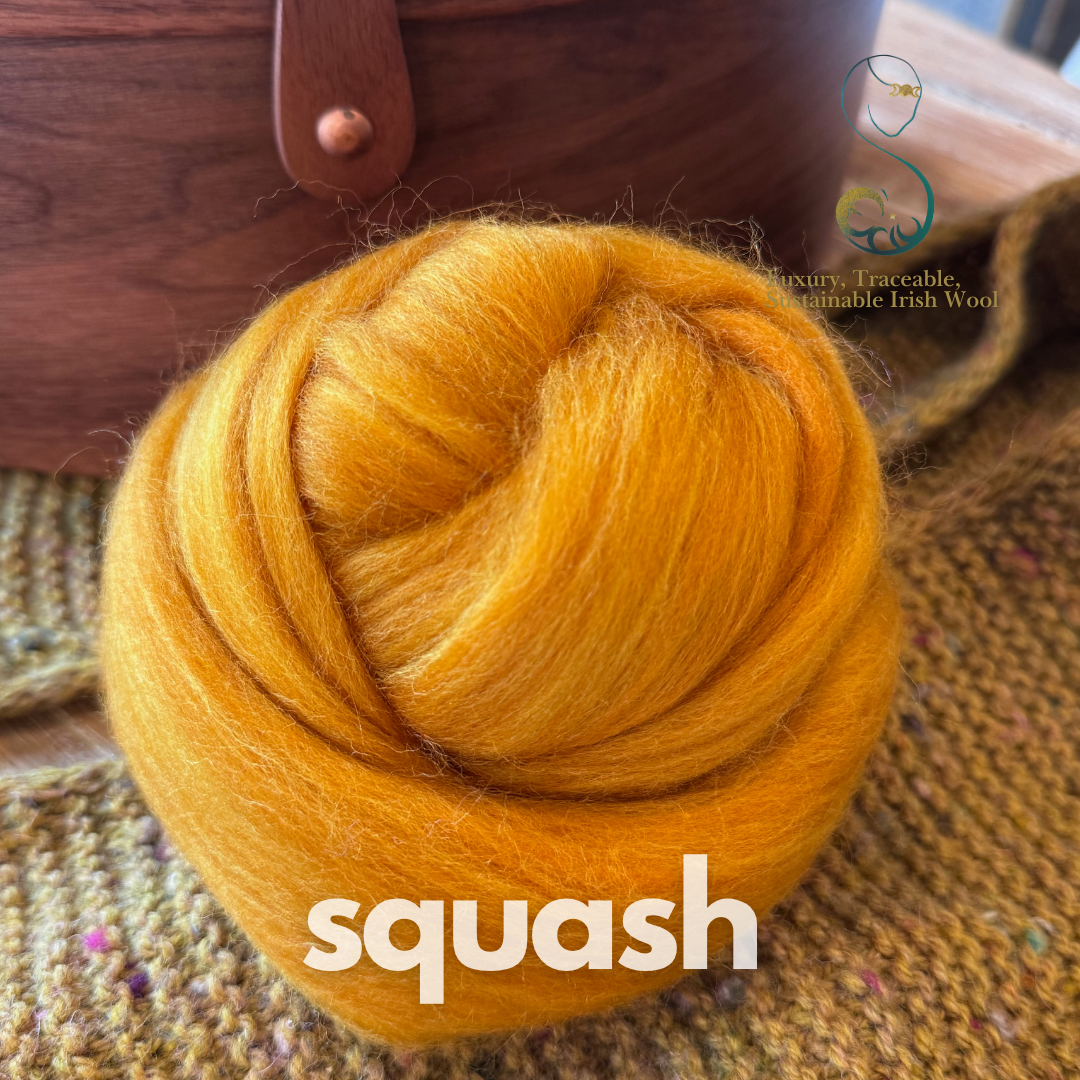 Ball of squash-colored combed top from BFL Irish sheep with a wooden basket in the background