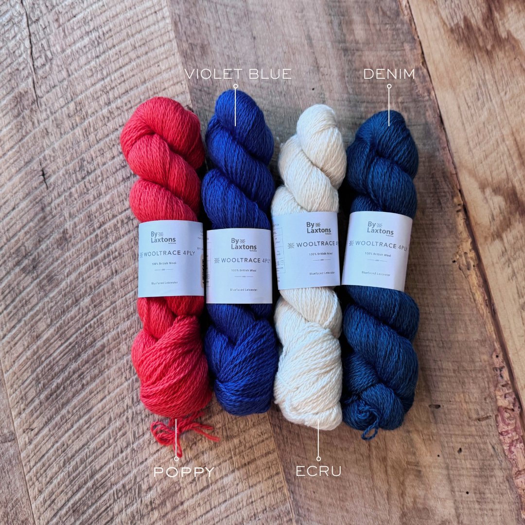 Four skeins of yarn in red, blue, and ecru on a wooden surface with labels indicating color names.