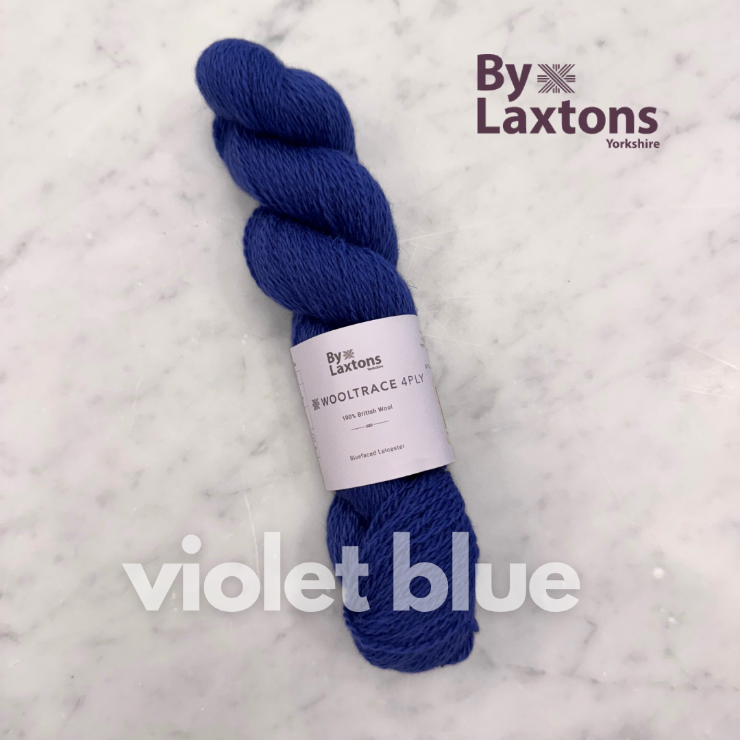 Blue yarn skein with By Laxtons label on a white marble background