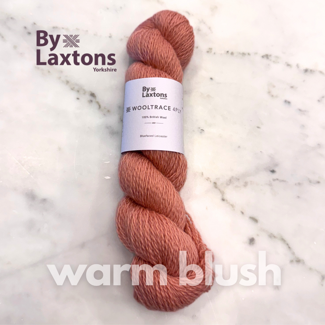 Blush coral hued pink Skein of yarn labeled 'By Laxtons' on a marble surface with 'warm blush' text.
