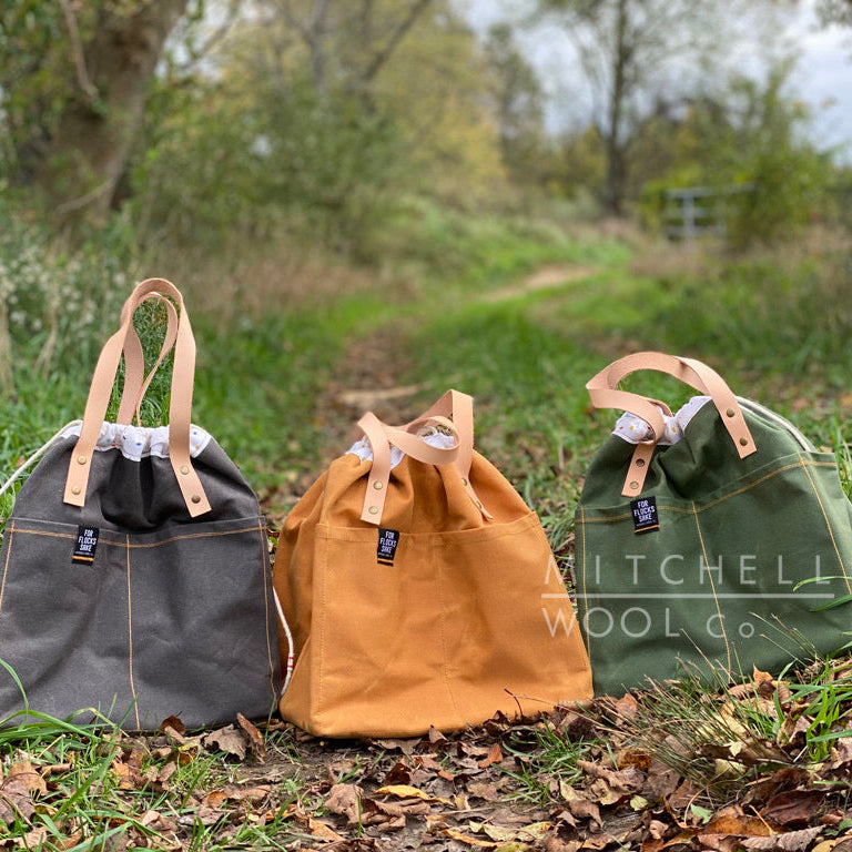 a grey, orange, and green bag sit on a grassy path